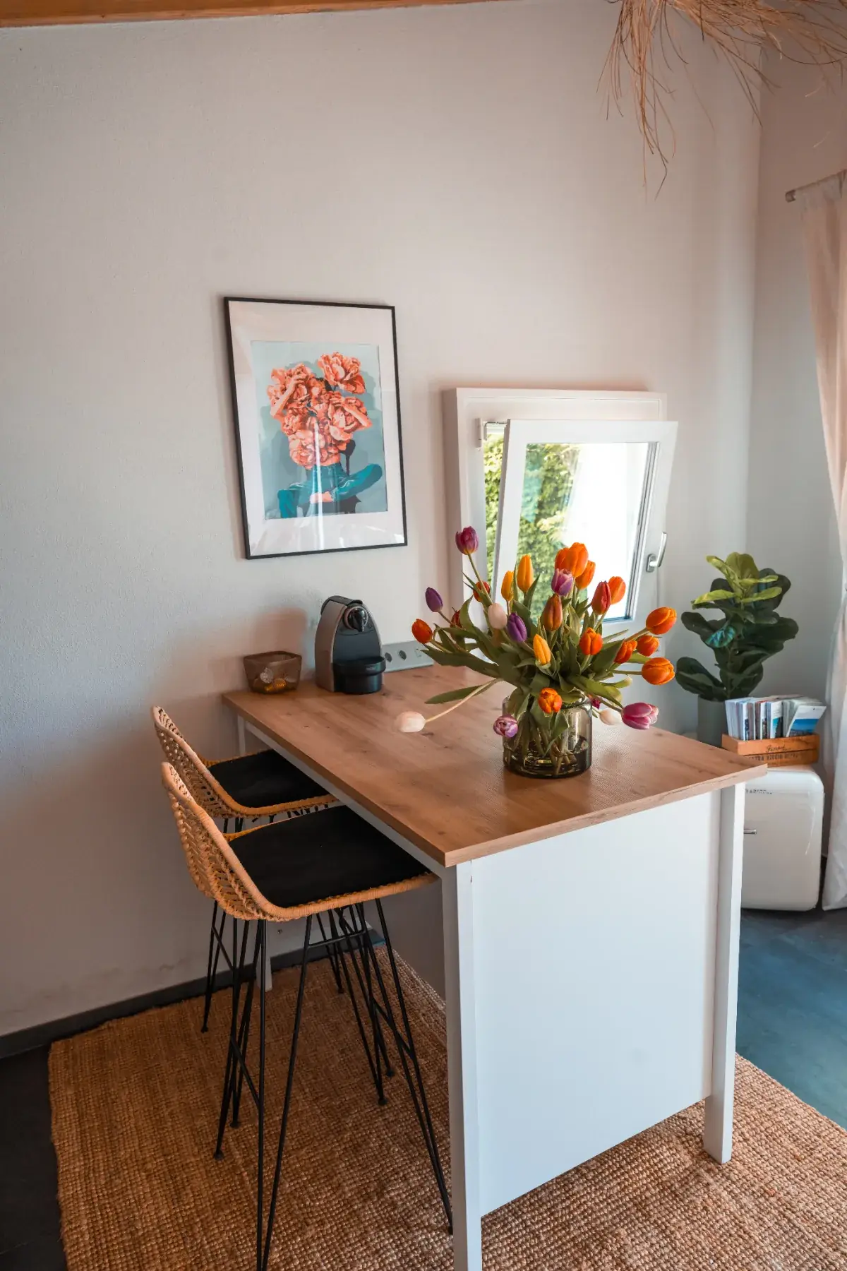 Coin repas du Cabanon des Vignes avec table haute, tabourets et bouquet de tulipes
